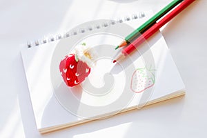 A knitted strawberry is lying on the album.