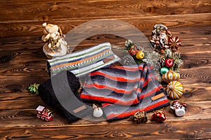 Knitted striped striped scarves, black knitted sleeves and Christmas toys on wooden background