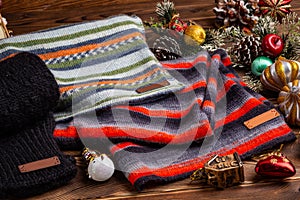 Knitted striped striped scarves, black knitted sleeves and Christmas toys on wooden background