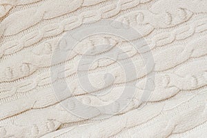Knitted textured background of light color with pattern, woolen knit fabric