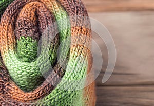 Knitted things with gradient wool on a wooden background. Copy space