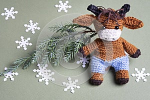 Knitted toy bull with Christmas tree and snowflakes on green background