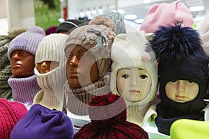 Knitted warm hats on the heads of mannequins in a shop window. Fashion in the cold season. Close-up