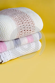 Knitted warm plaids of light color, bedding on a yellow background