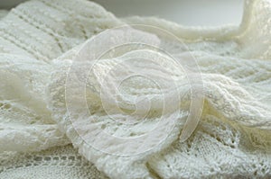 Knitted warm White scarf. Cozy composition in the home atrosphere. Wool fabric texture close up background. Comfortable style