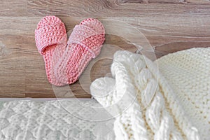 Knitted white bedspread and pink women`s Slippers near the bed