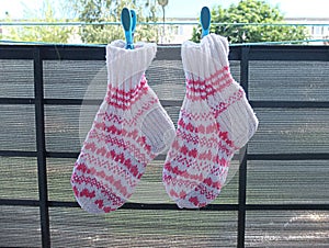 Knitted wool socks with abstract pattern hanging with clothespin on balcony