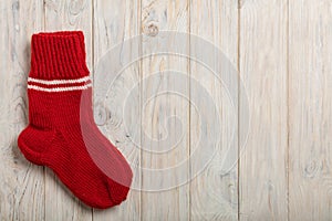 Knitted wool socks red color on light wooden background.