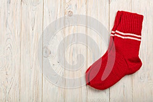 Knitted wool socks in red on a light wooden background.