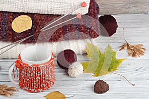 Knitted wool sweaters. Pile of knitted winter, autumn clothes on red, wooden background, sweaters, knitwear, ball, cup