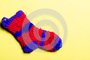Knitted woolen sock of red color with blue stripes on a yellow background