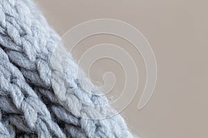 Knitted woolen textured surface on beige background. Macro. Soft grey merino wool pattern backdrop, closeup. Autumn and winter