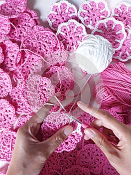 knitting or crocheting pink and white floral pattern. Handmade activity. Consist of yarn and needle hook for crochet.