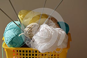 Knitting day. multicolored skeins of woolen threads and knitting needles in a yellow basket. handiwork.