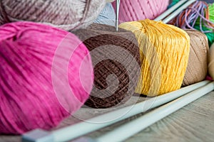 Knitting. Group of multicolor yarn and needles on grey wooden table. Close up.