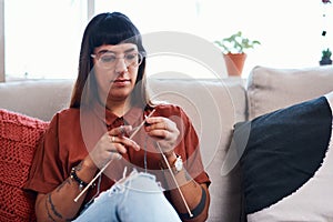 Knitting is like a meditation session. a young woman knitting while relaxing at home.