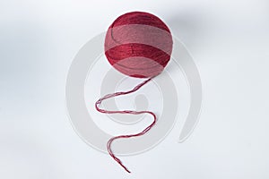 The knitting thread is unwound from a ball. A thread of burgundy color.