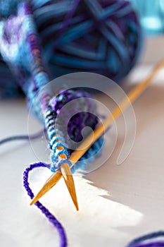 Knitting on wooden knitting needles from violet blue purple yarn close-up. Hobby, homemade