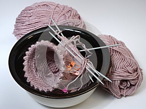 knitting from wool and knitting needles in a ceramic bowl