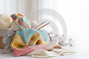 Knitting wool and knitting needles in pastel colors on white background. Cotton bolls. Copy space