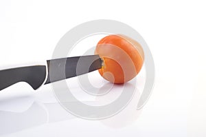 A knive cutting a tomato on white background