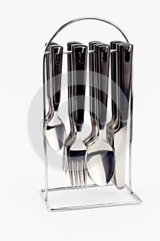 Knives, forks and spoons with black handles hanging on metal sta