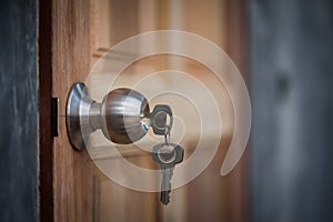 Knob, key and wooden door on gray background