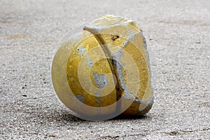 Knocked over old dilapidated and damaged concrete with rounded top light yellow parking lot security barrier