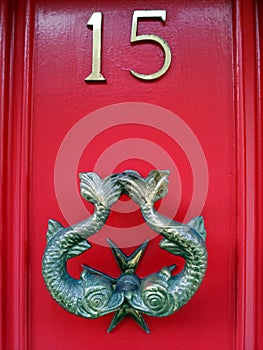 Knocker on red door number 15 with Pisces fish