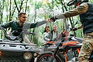 Knocking fists, gesture. Two couples on ATV with man that is on the bike in the forest