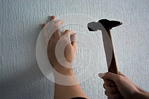 Knocking a nail into the wall with a hammer