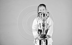 Knockout. energy and activity for kids. winner little girl in gi sportswear. small girl with champion cup. martial art