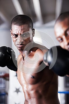 Knockout punch. An african american boxer delivering a knockout punch to his opponents jaw.