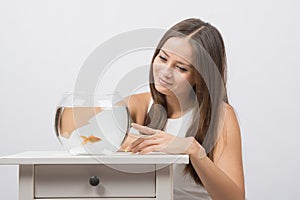 She knocks on the finger on the glass aquarium with goldfish