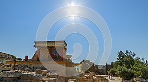 Knossos Palace ruin with sun and tourists in background, sunny day backlight, Greece, Crete