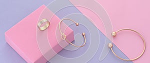 Knot shape modern bracelet and ring on pink and purple background with copy space