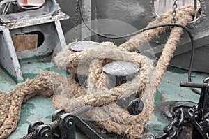 Knotted rope knot on a metal pole, seaport. The naval ship is moored in the dock.