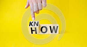 Know how symbol. Businessman hand points at turned wooden cubes with words How and Know. Beautiful yellow background. Business and
