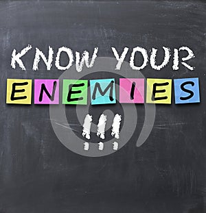 Know your enemies text on a blackboard with chalk and stickers