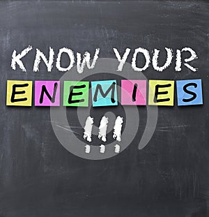 Know your enemies text on a blackboard with chalk and stickers photo