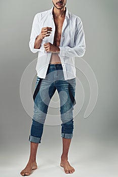 Know your style and wear it well. Studio shot of a handsome young man wearing jeans and a white shirt against a grey