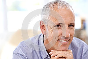 A knowledgable smile. Portrait of a happy mature man relaxing at home. photo