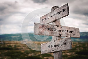 Knowledge, character and respect  text on wooden rustic signpost outdoors in nature/mountain scenery.