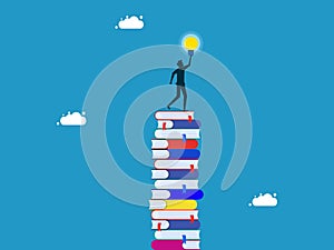 knowledge creates opportunities and wisdom for creative thinkers. Businessman on a high stack of books with a light bulb