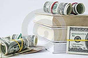 Knowledge leads to wealth. Stack of books with dollars. Concept of expensive education. Money in books. Saving money for