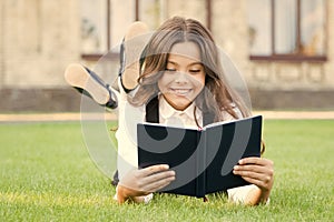 Knowledge is more than information. Happy small girl read book on green grass. Adorable little schoolchild get knowledge