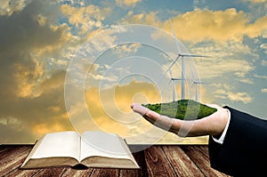 Knowledge for wind energy concept, Open book with wind turbine in hand of business man