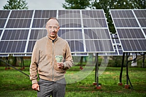Knowledgeable man showing money he earning by investing in green energy.