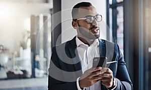 He knows all the right people to connect with. a young businessman using a cellphone in an office.