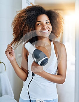 She knows how to care for curly hair. an attractive young woman drying her hair with a hairdryer at home.
